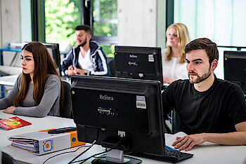 Kursteilnehmer und Kursteilnehmerinnen sitzen konzentriert an den PC-Bildschirmen im IT-Schulungsraum am ELBCAMPUS
