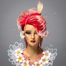 Geschminkter Frisierkopf mit roten Haaren und Blumenaccessoires aus einer Meisterprüfung am ELBCAMPUS