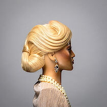 Frisierkopf aus einer Meisterprüfung mit langen blonden Haaren und einer Perlenkette